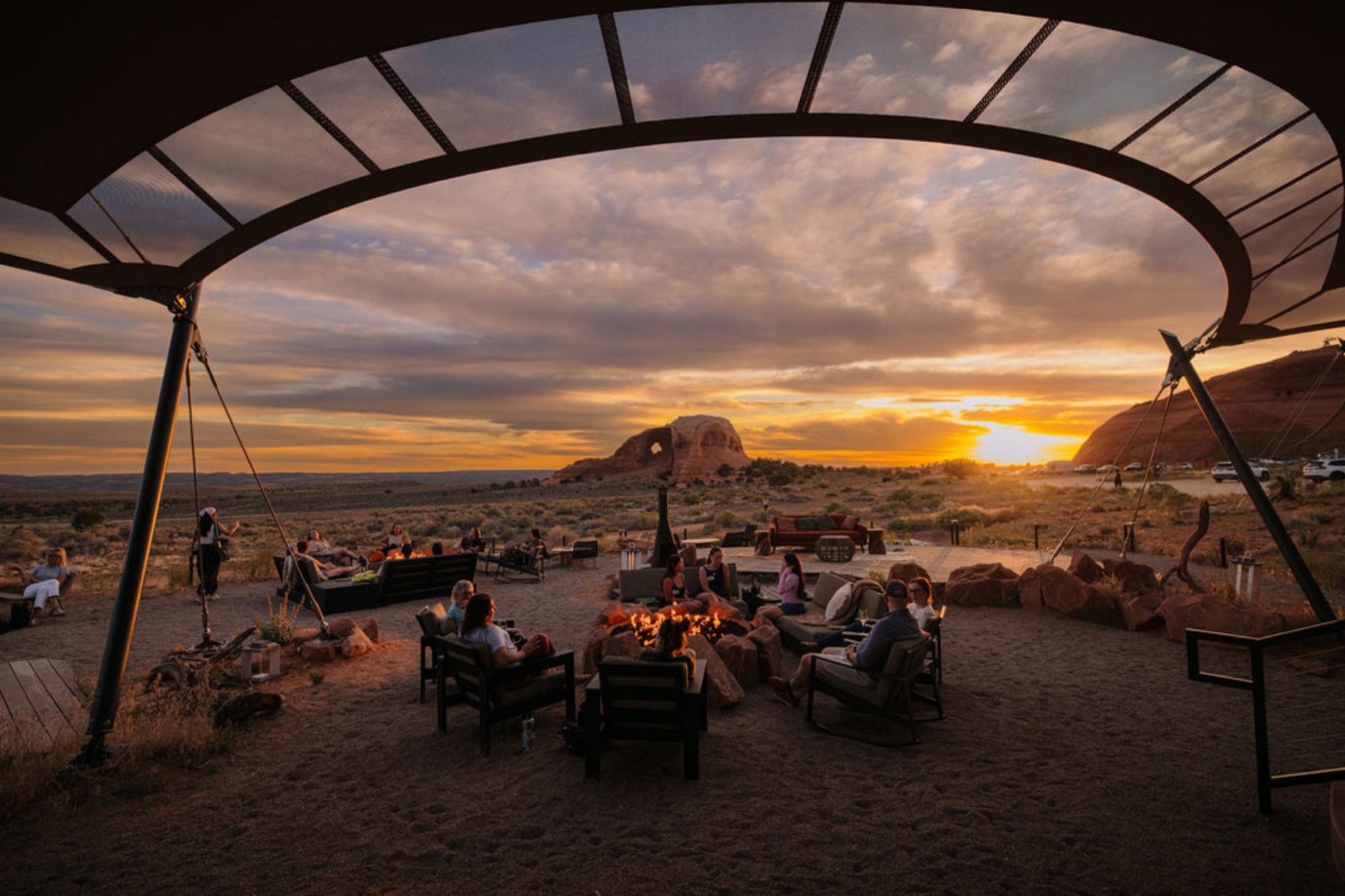 Camp Unwritten guests gathered around fire pits at sunset in Moab