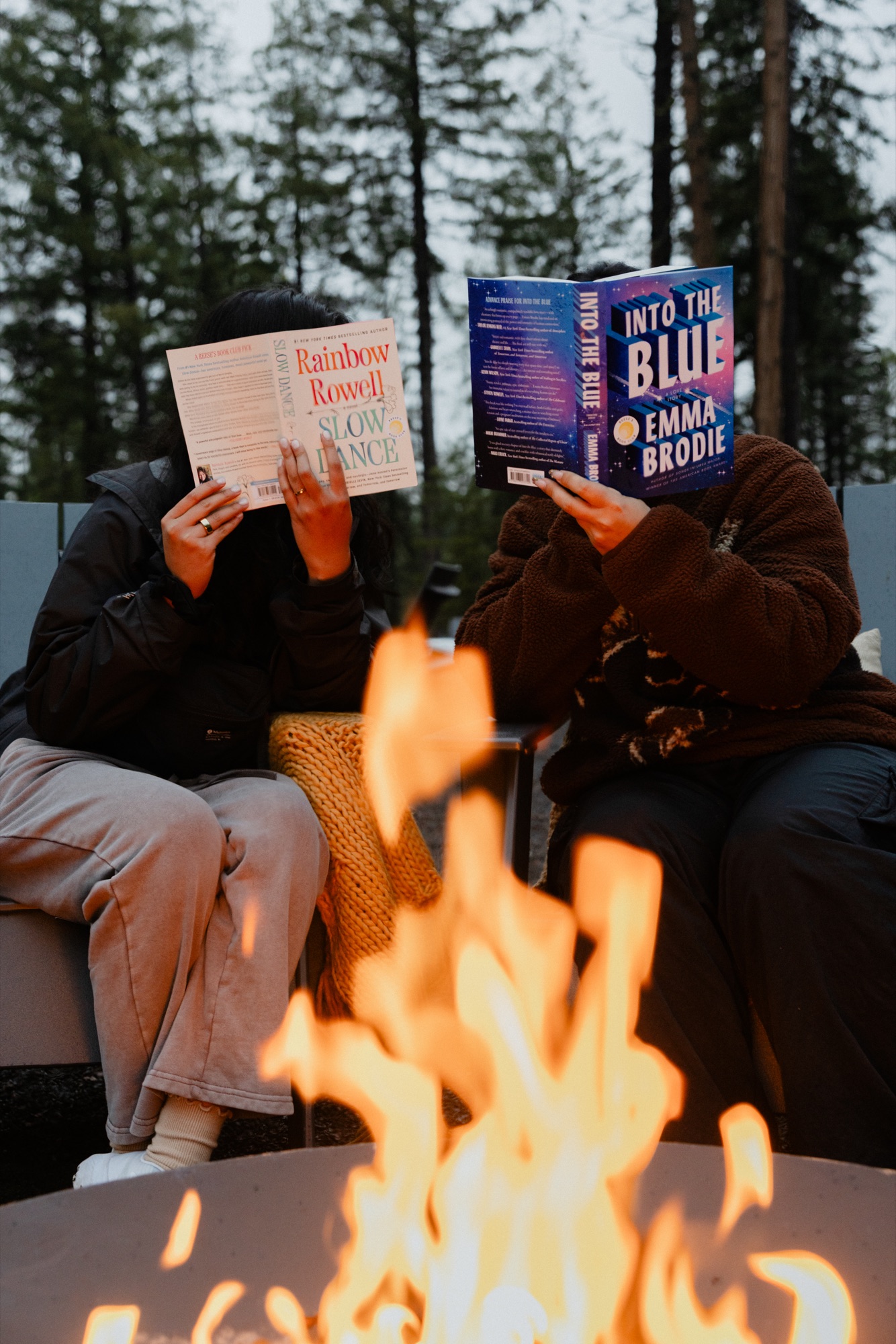 Two readers holding books beside a fire in Yosemite