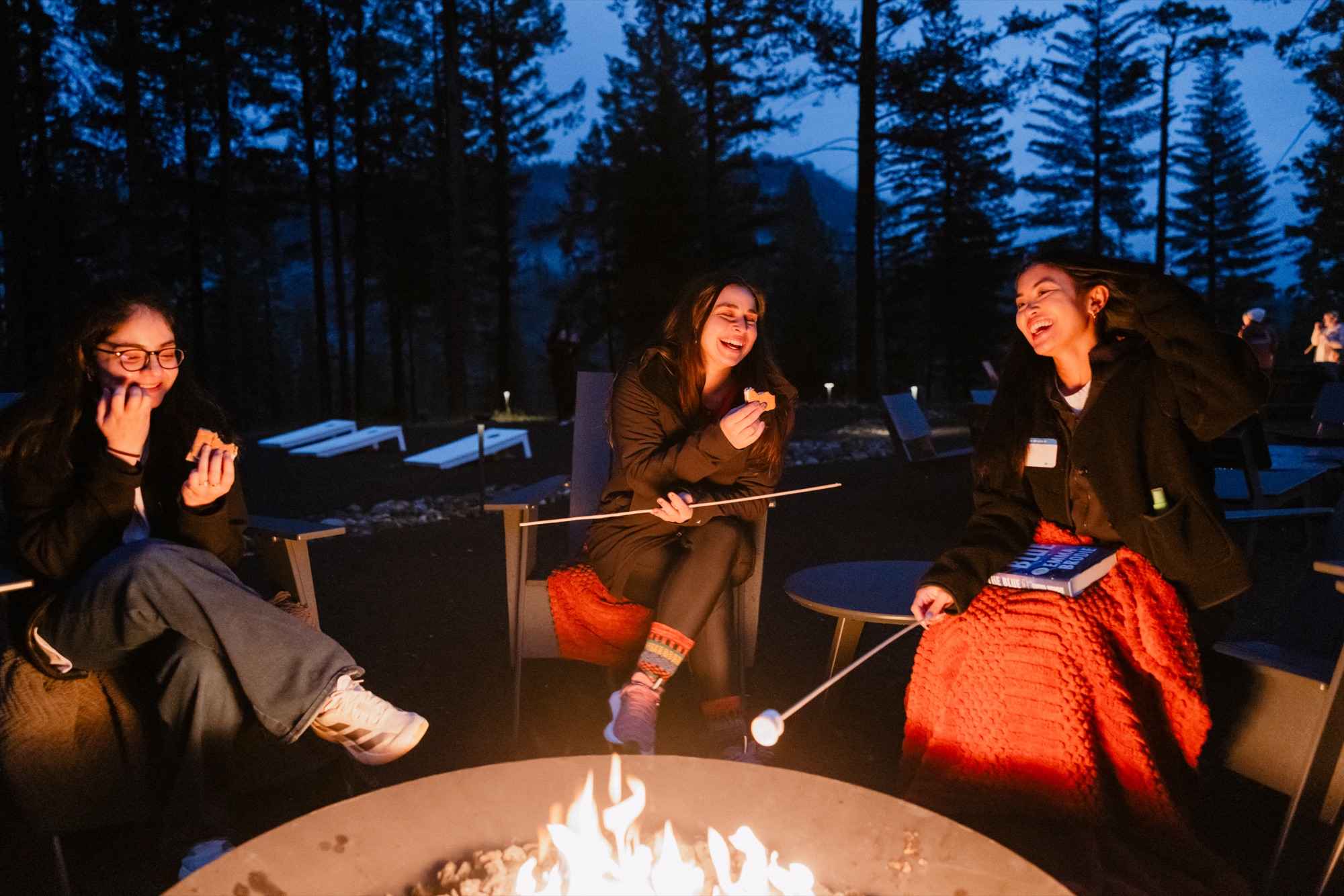 Camp Unwritten guests laughing around a campfire in Yosemite