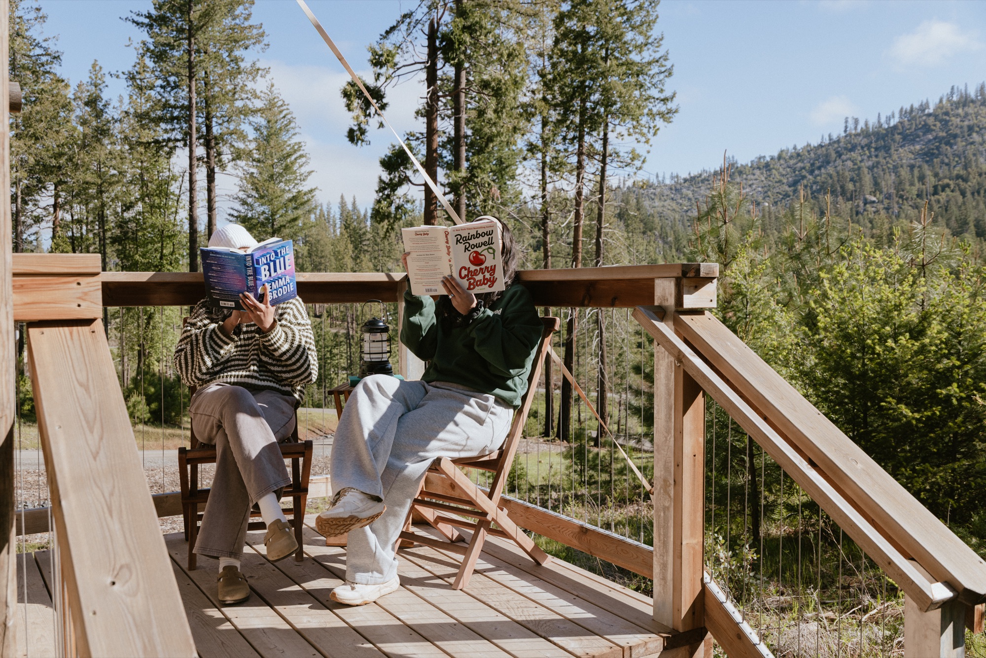 Two Camp Unwritten guests reading together on a sunny deck in Yosemite