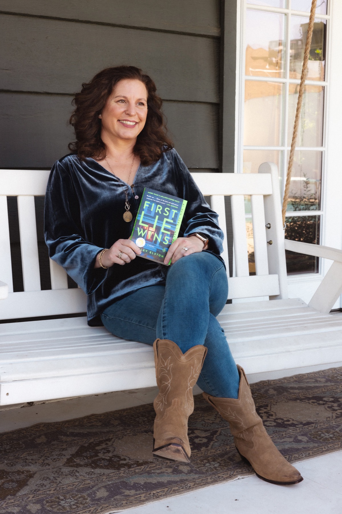 Ashley Elston seated on a porch holding First Lie Wins.