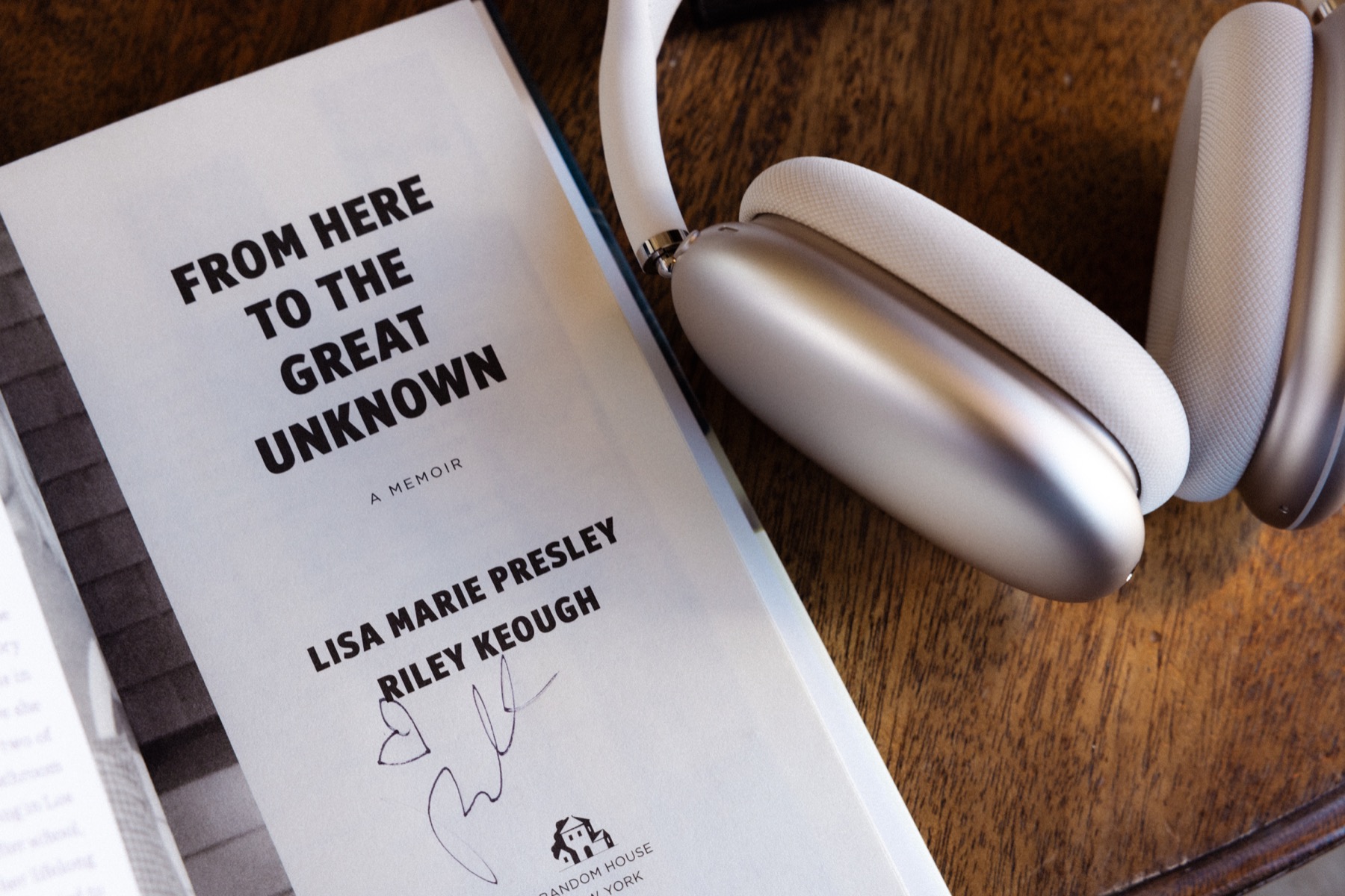 A signed copy of From Here to the Great Unknown beside headphones.